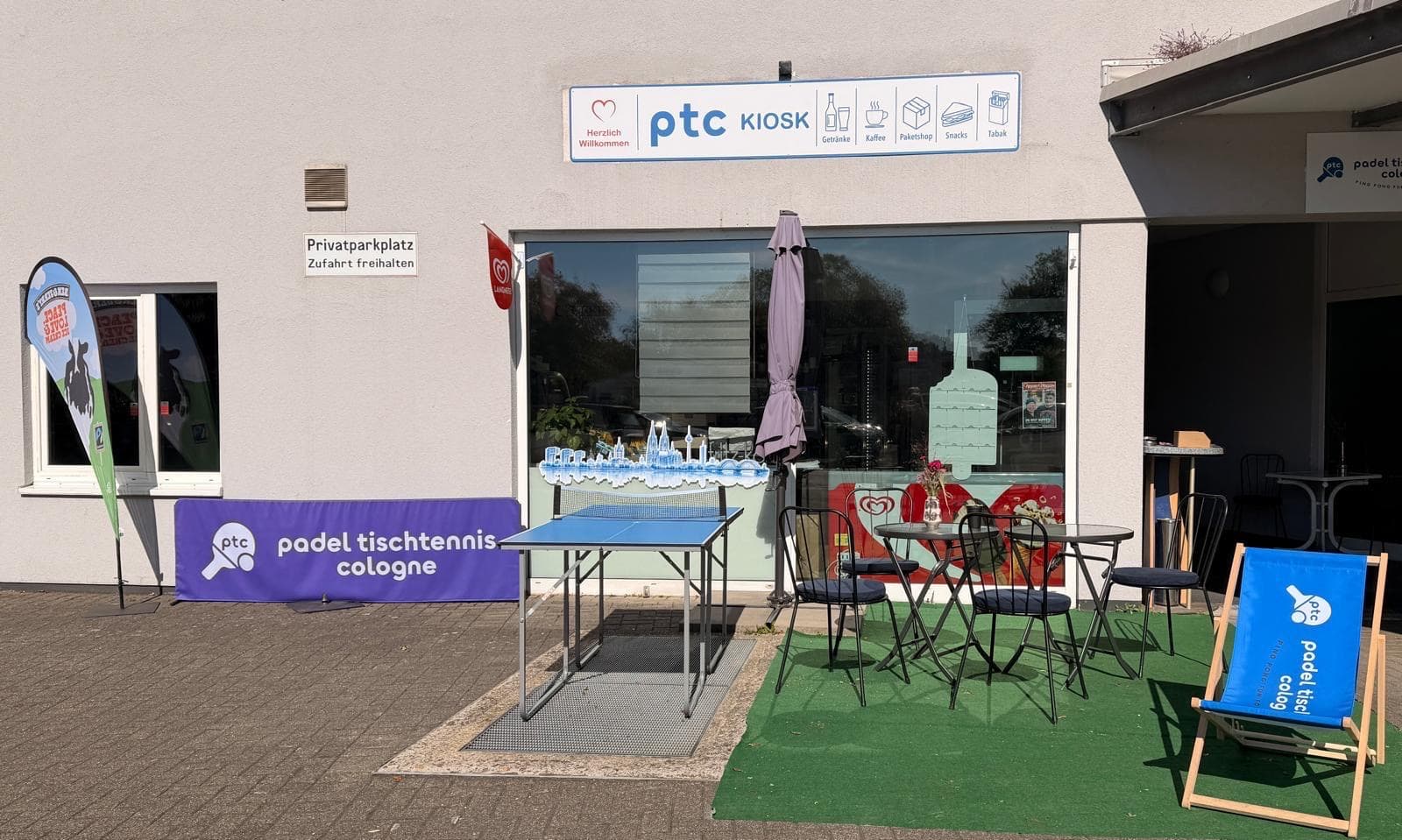 Der ptc KIOSK von außen mit Tischtennistisch, Terrasse und Liegestuhl